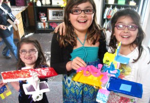 girls holding artwork made of recycled and upcycled materials