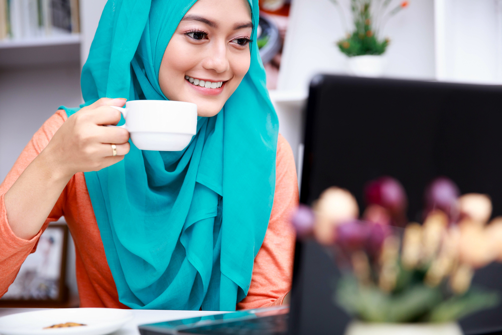 muslim woman drinking tea on computer