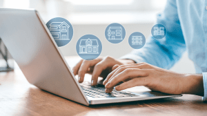 man typing at laptop with graphics of residential buildings floating above his hands