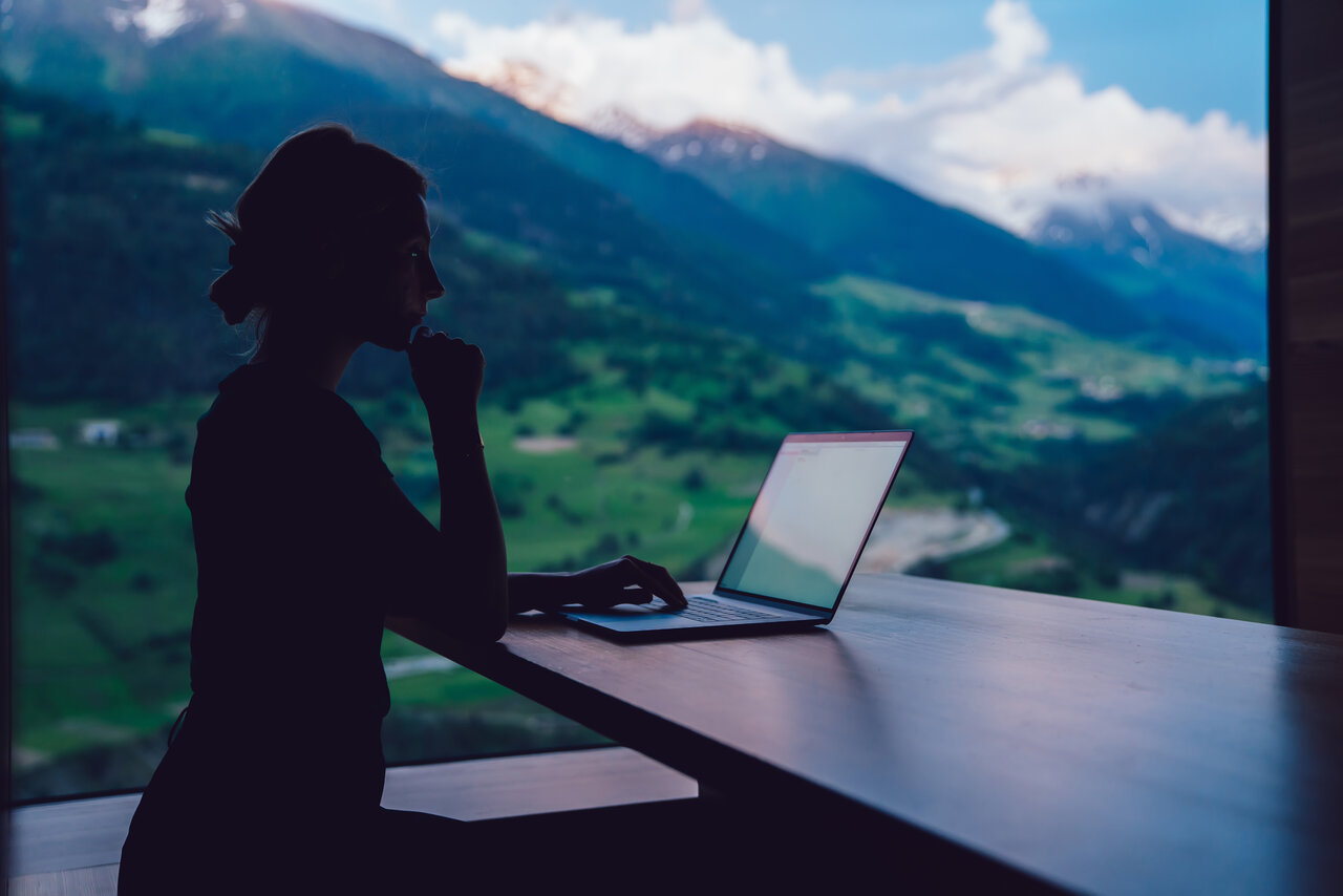 Silhouette view of woman digital nomad working with business project via netbook application, female freelancer watching video on laptop computer typing content publication. Remote work