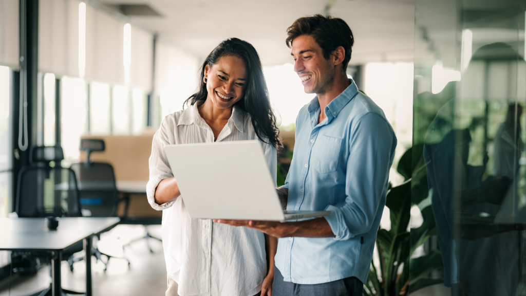 Two people smiling and holding a laptop