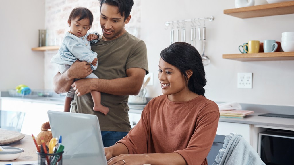 Family of three looking at a laptop in home setting