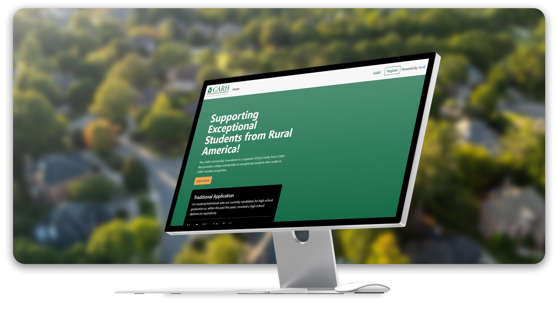 A computer monitor displays the CARH website with green trees and vegetation blurred in the background