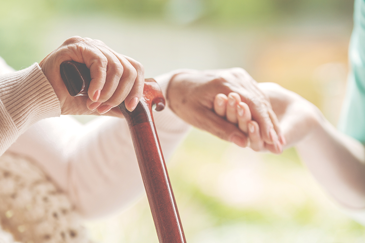 Closeup of senior lady holding walking stick in one hand and hol
