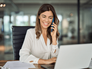 A woman talking on a phone while typing on a computer. Representing Contact IQ's internal routing features.